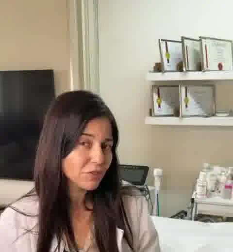 מיכל פאר בקליניקה הביתית שלה בראשון לציון, ברקע תעודות הסמכה ומיטת טיפולים